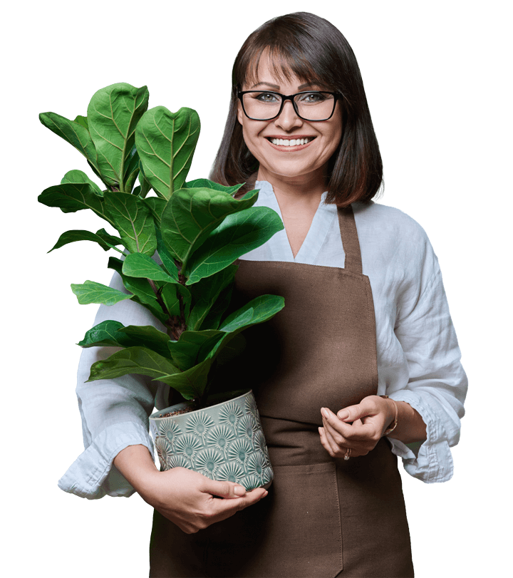 Femme souriante tenant une plante en pot dans un cache-pot décoratif.